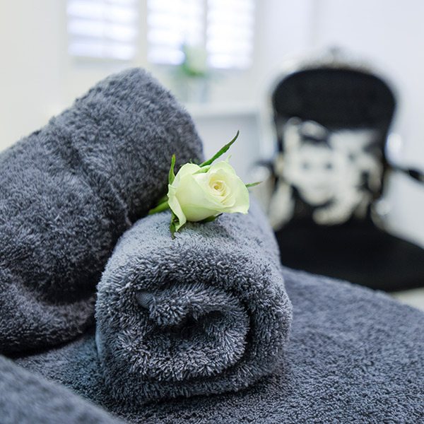 Towels & a white rose set up for treatment at Hunter House Clinic